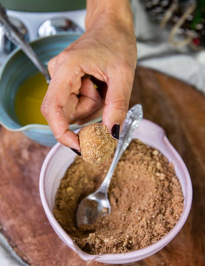 The dough is now dipped into a bowl of cinnamon sugar and coated well using a spoon