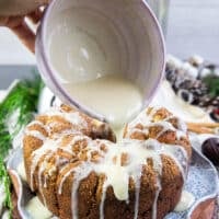 A hand pouring the cream cheese icing over the monkey bread generously