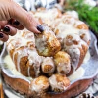 A hand holding a piece of cinnamon roll monkey bread showing how soft it is
