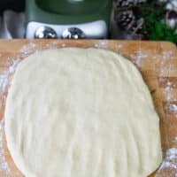 the monkey bread dough is patted down into a rectangle over a wooden board
