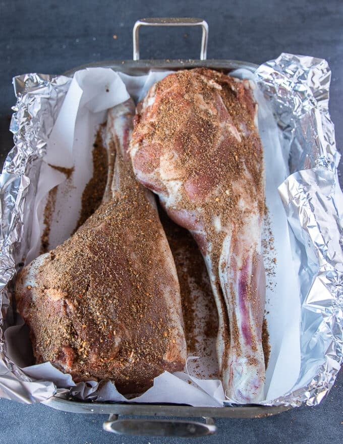 The leg of lamb in a roasting pan lined with foil and parchment paper, and with the dry spice blend all over it