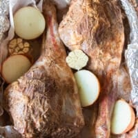 marinated leg of lamb in a roasting pan and ready to roast with adding onions, bay leaves, stock and whole spices