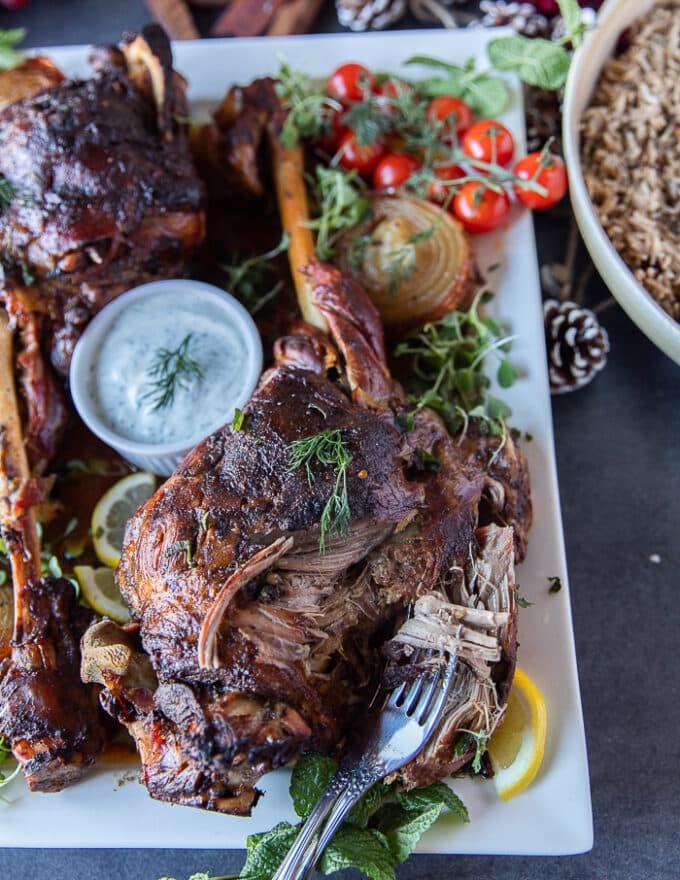 A fork breaking apart the roast leg of lamb recipe showing how fall off the bone it is