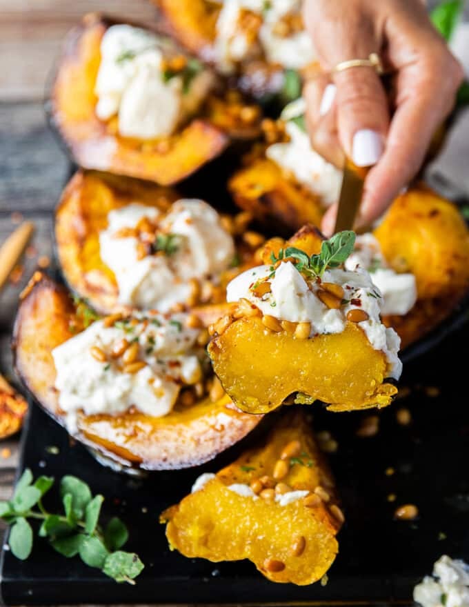 A hand holding a cut up piece of roasted acorn squash to show the texture