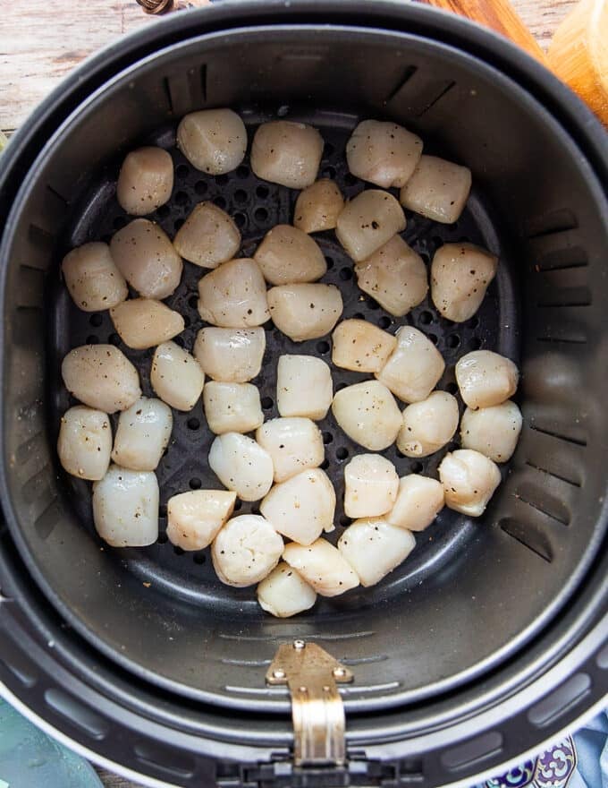 Scallops arranged in a single layer in the air fryer basket ready to cook 