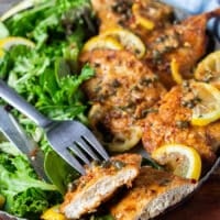 A fork holding a cut up piece of chicken scallopini showing how juicy the chicken is on the inside and how beautiful the crust is on the outside