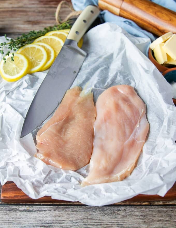 paper thin chicken breasts sliced on a parchment paper ready for breading to make chicken scallopini recipe