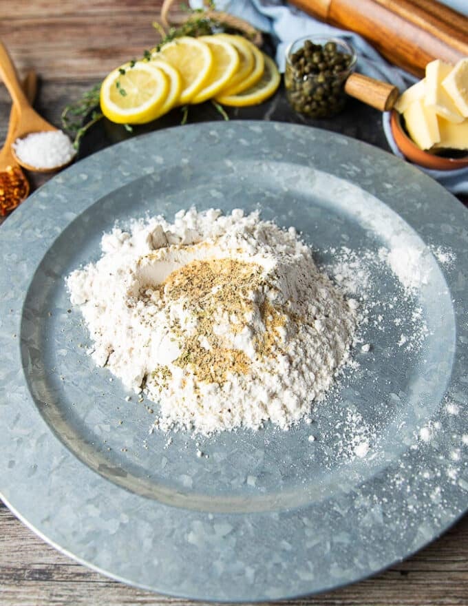 A large shallow plate of flour with seasoning added on top 