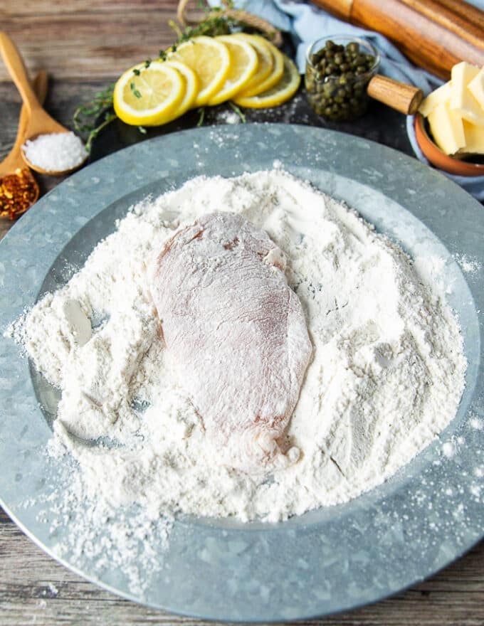 Chicken breasts placed in the shallow plate of seasoned flour and covered on both sides