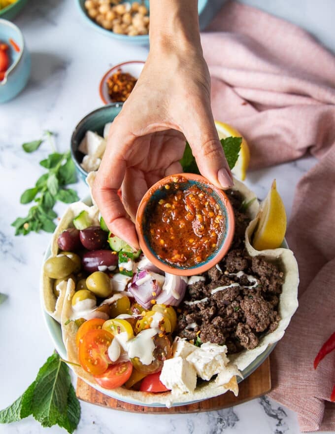 A hand showing some hot pepper sauce made to add over the bowls