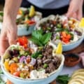 A hand holding two pita bowls loaded with toppings and lined iwth pita bread
