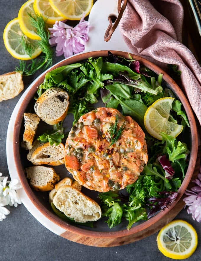 Top view of a finished salmon tartare recipe showing the beautiful salmon tarter stacked with avocados, spices, herbs, shallots and olive oil