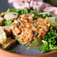 Side view of the salmon tartare recipe showing the beautiful layers of avocado and salmon stacked up into a delicious and gorgeous looking dish