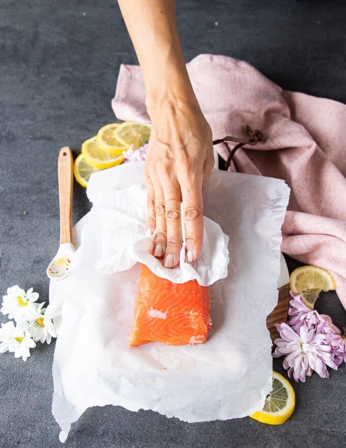 A hand patting down the salmon to make the tartare recipe with a paper towel 