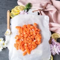 Salmon fillet is cut into small cubes , chunks of half an inch over the parchment paper lined board