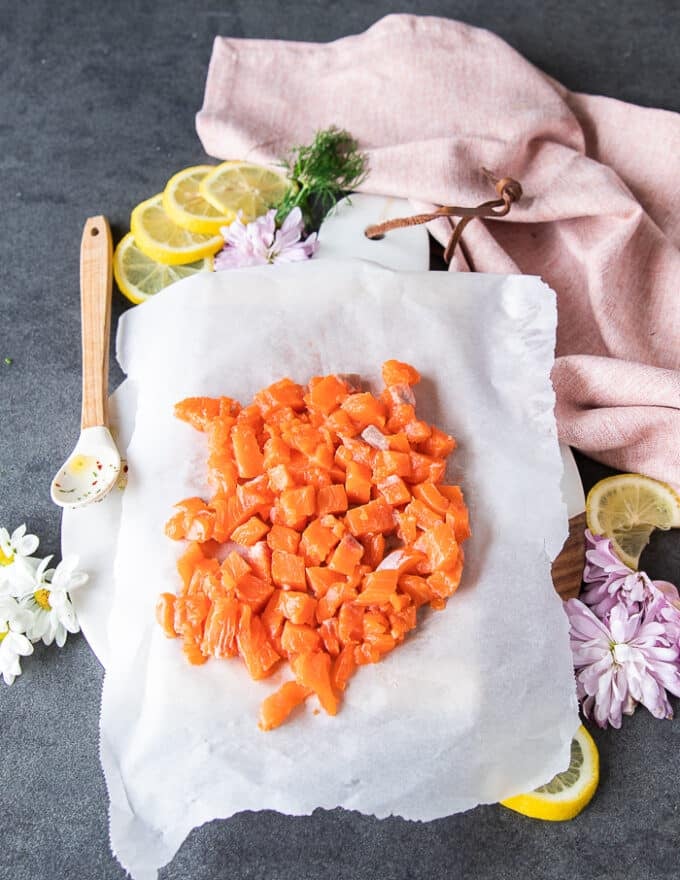 Salmon fillet is cut into small cubes , chunks of half an inch over the parchment paper lined board