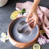 A hand holding a large round ring mold to stack up the salmon tartare