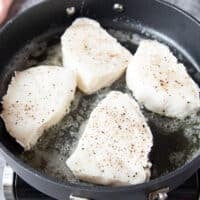 Chilean sea bass seasoned with salt and pepper in a hot skillet