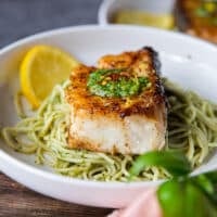 one plate of cooked chilean sea bass over a bowl of lemon pasta
