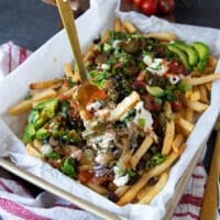 A hand holding a fork grabbing some nacho fries