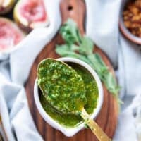 A spoon showing the dripping chermoula sauce over a bowl