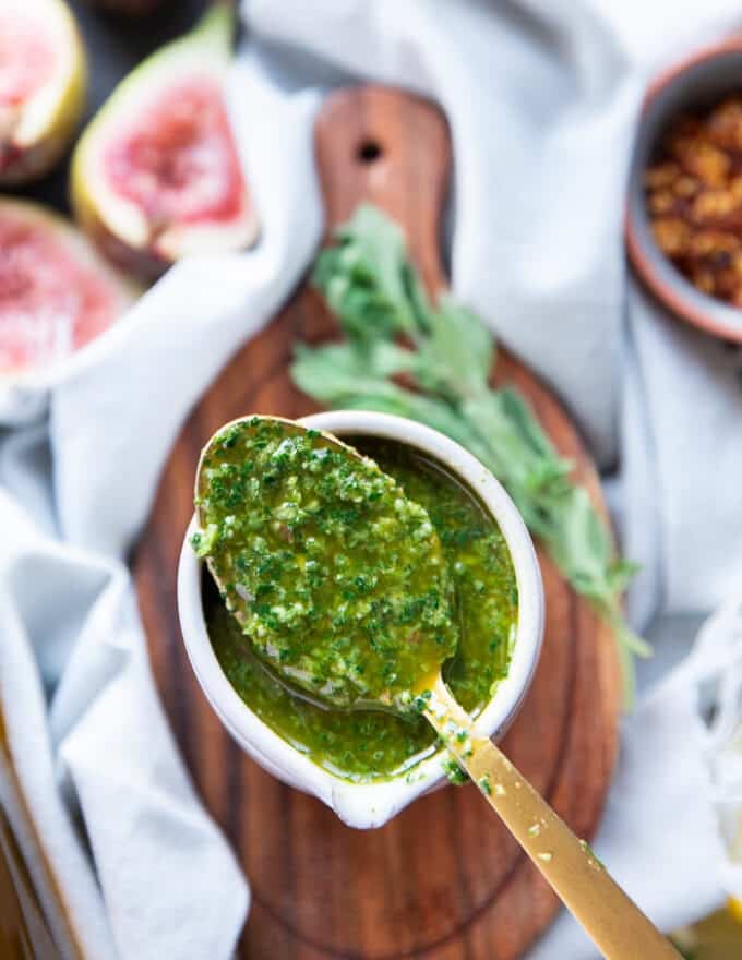 A spoon showing the dripping chermoula sauce over a bowl