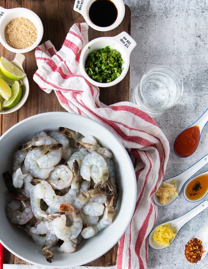 ingredients for the chili lime shrimp including raw, peeled and deveined shrimp, some lime, cilantro, chillies, soy sauce, brown sugar, sesame oil, ginger, garlic, hot sriracha sauce, lime juice, water, 