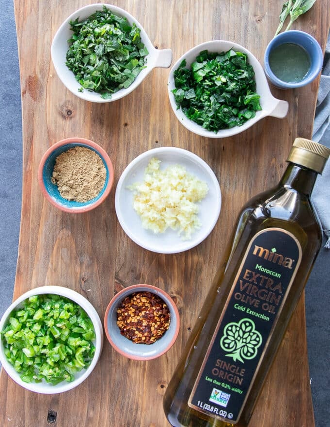 ingredients for sardine recipe including garlic, lemon, chilli flakes, olive oil, seasoning, and minced herbs