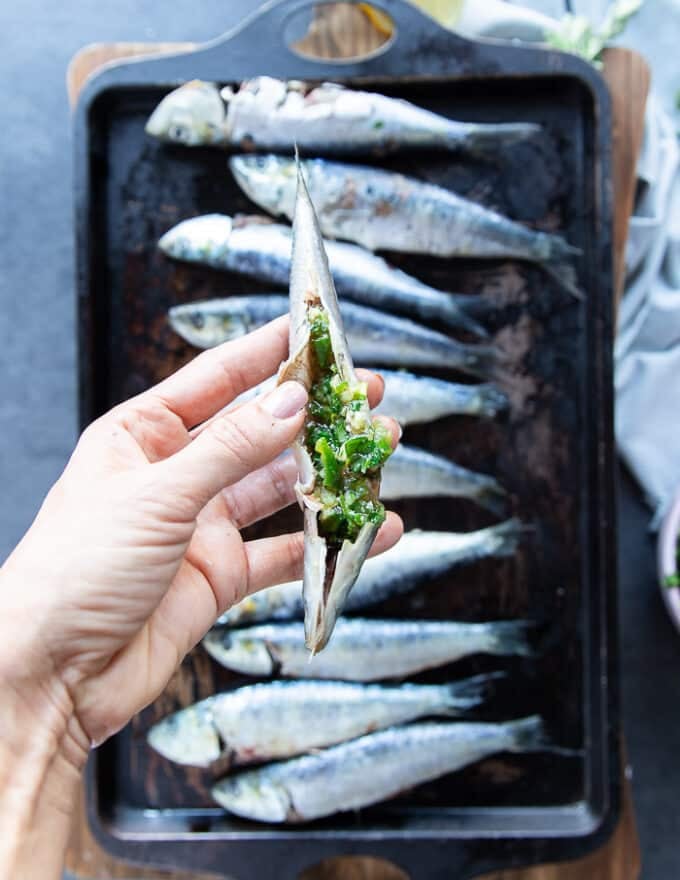 a hand holding one ready and flavored sardine