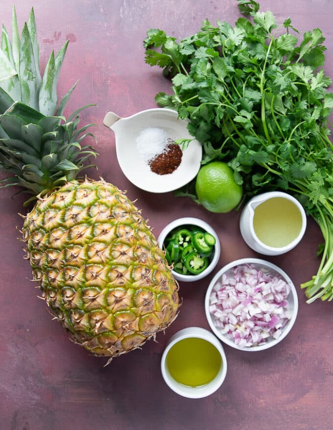 Pineapple Salsa ingredients including pineapples, onions, lime juice, jalapeno, cilantro, olive oil, seasoning