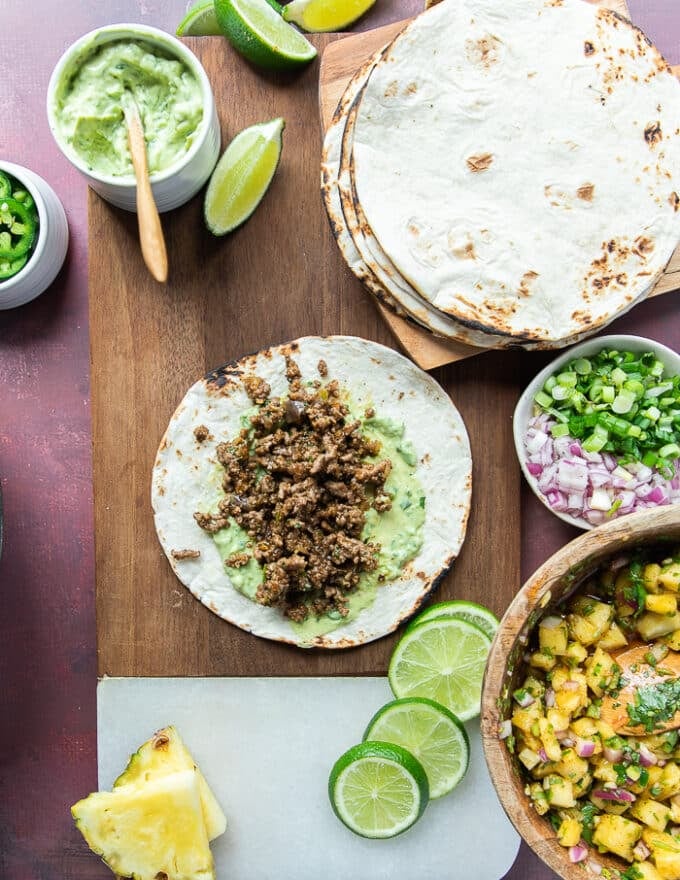 Assembling the lamb tacos step by step, now adding the lamb meat over the avocado crema