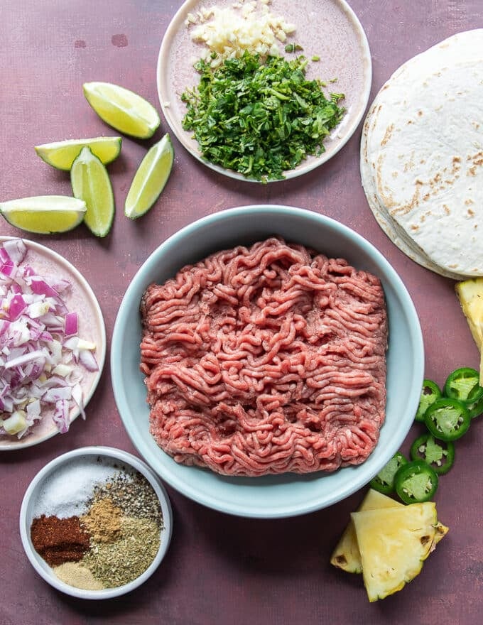 Ingredients for lamb tacos including lamb, tortillas, onions, spices, garlic, cilantro, jalapeno
