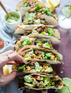 A hand placing the assembled lamb tacos on a taco holder