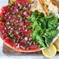 close up of a dressed up tuna carpaccio on a serving platter