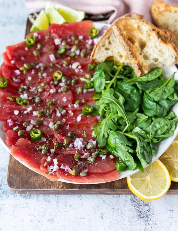close up of a dressed up tuna carpaccio on a serving platter