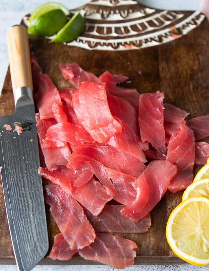 All the saku tuna blocks thinly sliced on a wooden board using a very sharp knife