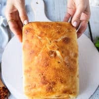 A hand holding the bread for the caprese sandwich showing the type of bread used focaccia