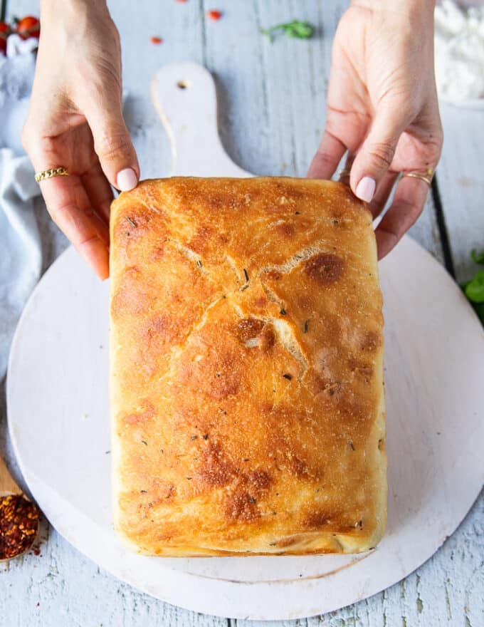 A hand holding the bread for the caprese sandwich showing the type of bread used focaccia