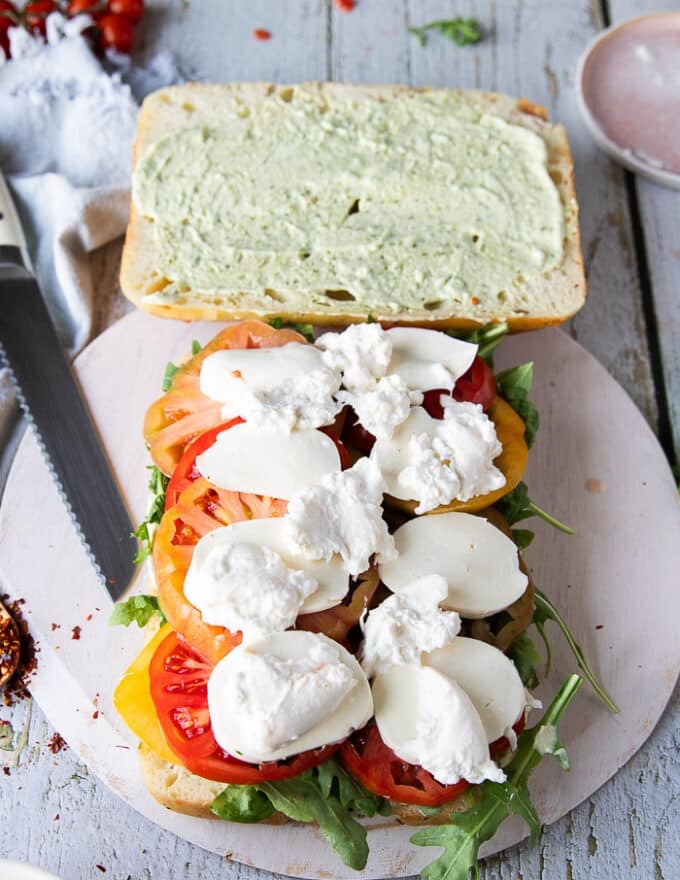 Fresh mozzarella slices and burrata go on top of the tomatoes for the caprese sandwich