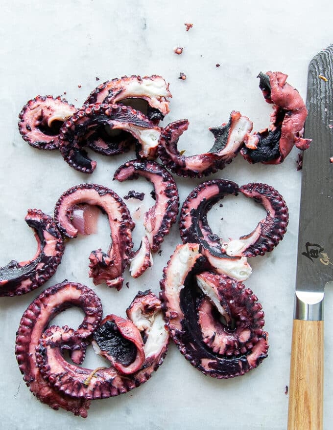 A knife slicing the tentacles of the boiled octopus