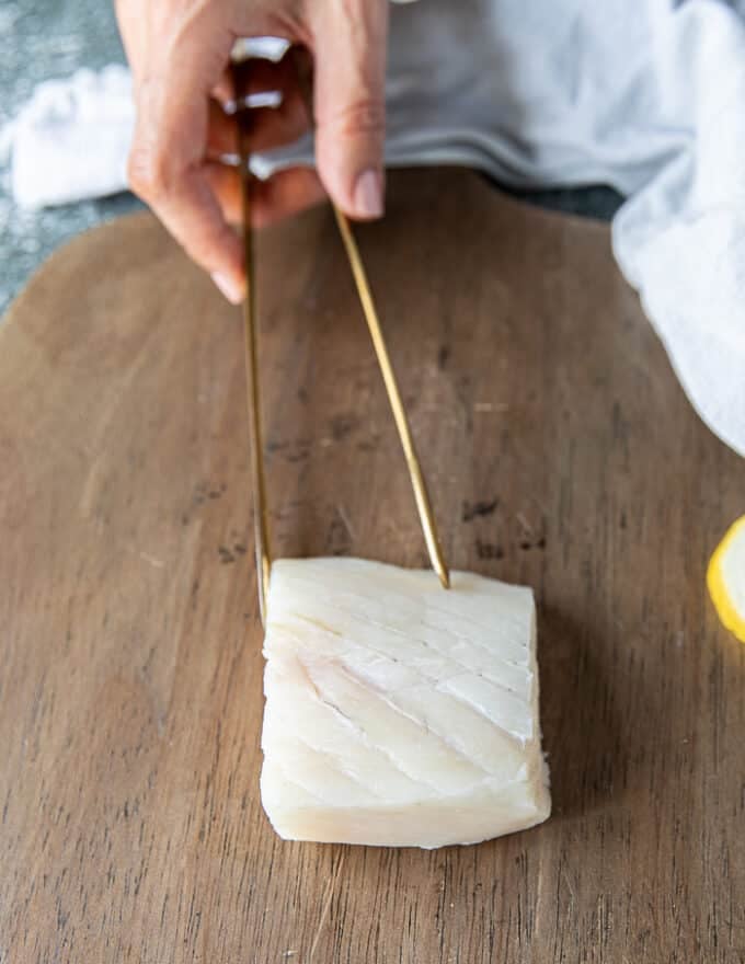 A piece of halibut fillet on a wooden board close up showing the texture and grain of the firm white fish