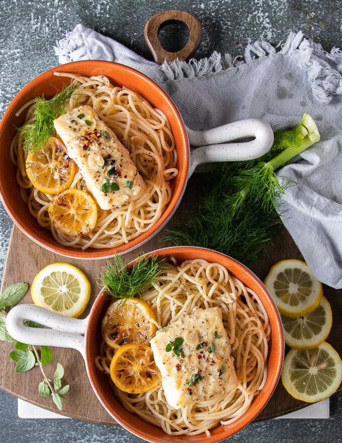 two bowls of lemon pasta with baked halibut served on top