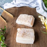 Halibut fillets on a wooden board seasoned with just salt and pepper