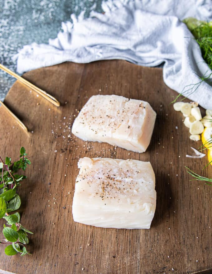 Halibut fillets on a wooden board seasoned with just salt and pepper