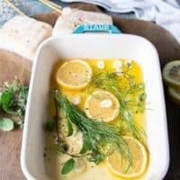 The bottom of the oven safe dish is then layered with sliced garlic, lemon slices and fresh herbs before the halibut fish is added.