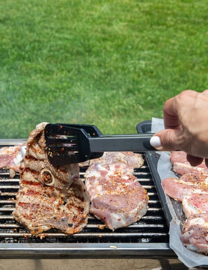 a hand flipping a grilled steak on the charcoal grill to show the grill marks