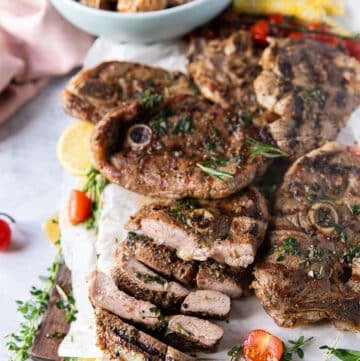 grilled lamb steaks on a platter with on steak sliced into strips to show the inside of the steak