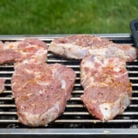 lamb steaks placed on a charcoal grill