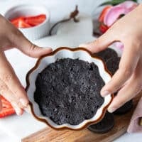 A hand holding the oreo mug cake right our of the microwave