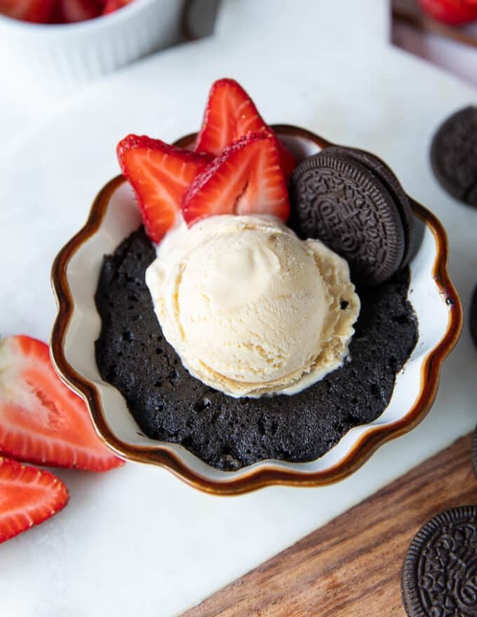 A perfectly made oreo mug cake served with ice cream, oreo cookies, strawberries ready to be served